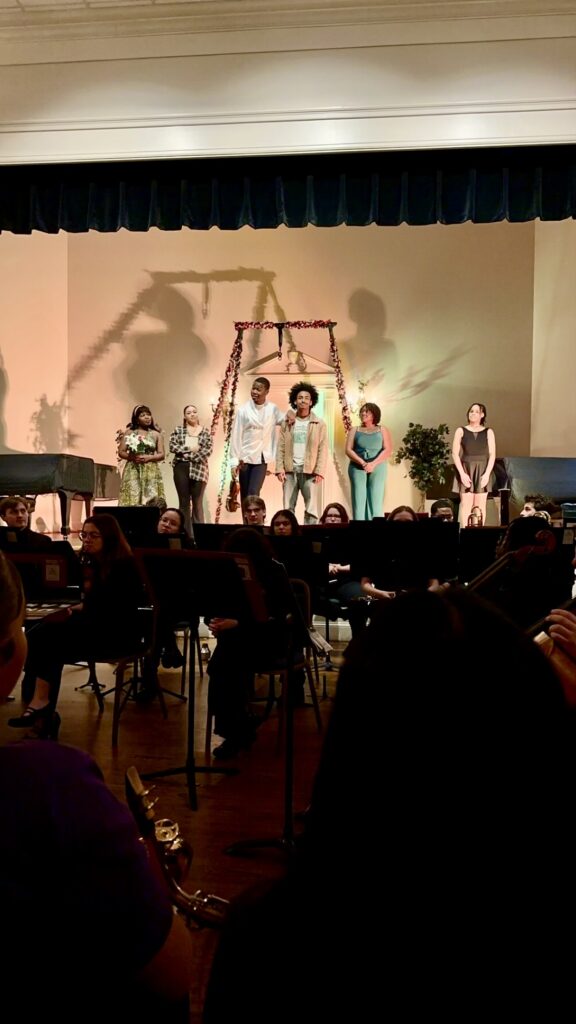 performers bow behind orchestra