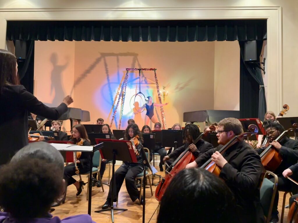 CC orchestra with aerial hoop performer in background
